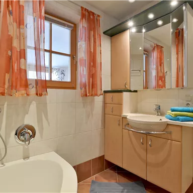 A modern bathroom with a bathtub and shower. Bright colors and large windows create a friendly atmosphere.