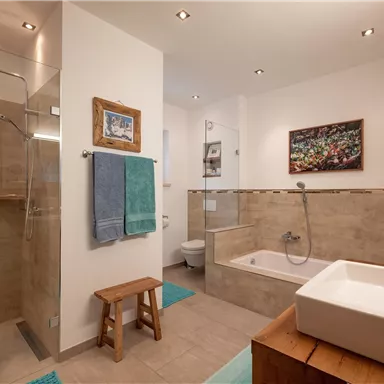 Ein modernes Badezimmer mit Dusche, Badewanne und Waschbecken. Es gibt elegante Fliesen und eine dekorative Wandmalerei.