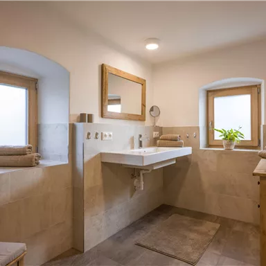 A modern bathroom with bright walls and a large sink. The room has windows that let in a lot of light and wooden decorations.