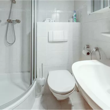Ein modernes Badezimmer mit einer Duschkabine und einer Badewanne. Die Wände sind hell gefliest und es sind Pflegeprodukte sichtbar.