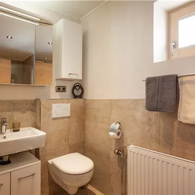 Ein modernes Badezimmer mit einer eleganten Waschtischanlage und großen Spiegeln. Es gibt Handtücher und eine helle Fensteröffnung, die für Tageslicht sorgt.