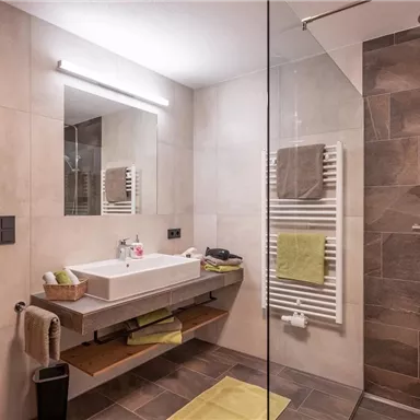 Ein modernes Badezimmer mit einer großen Dusche und einem eleganten Waschbecken. Die Wände sind hell und es gibt eine tolle Beleuchtung.