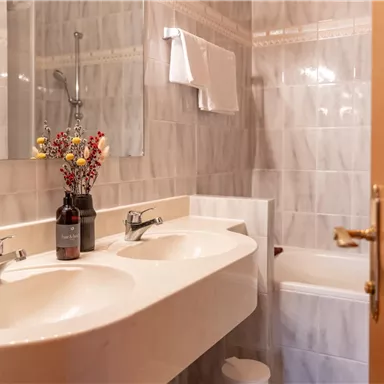 A modern bathroom with a double sink and a mirror. A pretty flower decoration adds an inviting touch.