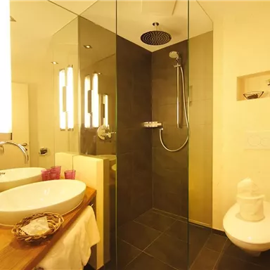 A modern bathroom with a glass shower and an elegant bathtub. The decorative details and soft lighting create a relaxing atmosphere.