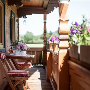 An inviting balcony with a wooden table and colorful flowers. The sunny view invites relaxation.