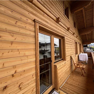 Ein Holz-Balkon mit einem Blick auf die Umgebung. Der Balkon ist gemütlich und einladend gestaltet.