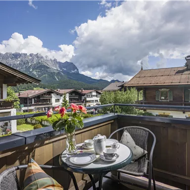 A cozy balcony overlooking the mountains. A table with a teapot and fresh flowers invites you to relax.