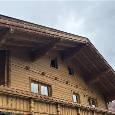 Ein traditionelles Holzhaus mit einem großen Dach. Der Himmel ist bewölkt.