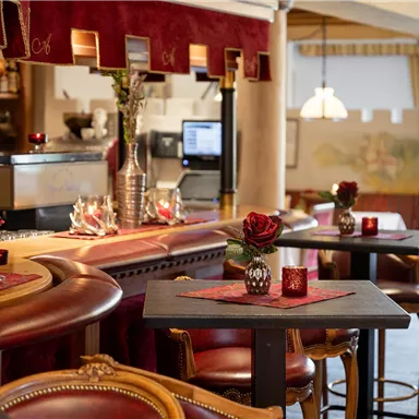 Ein gemütliches Restaurant mit einem Holzbar und eleganten Tischen. Die Atmosphäre wird durch Blumen und Kerzen verschönert.