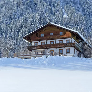 A charming wooden house in a snowy landscape. Surrounded by snow-covered trees and mountains.