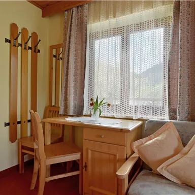 A cozy living area with a table, chairs, and a sofa. The window lets in a lot of light and creates an inviting atmosphere.