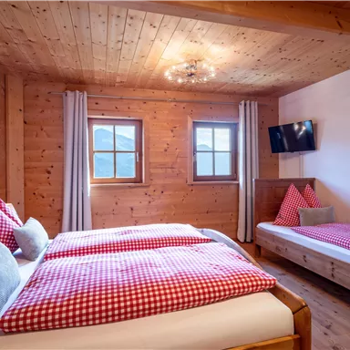 Ein gemütliches Zimmer mit Holzverkleidung und zwei Betten. Es gibt Fenster mit Ausblick und einen Fernseher an der Wand.