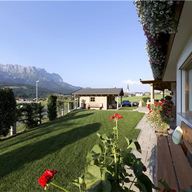 A picturesque landscape with green meadows and mountains in the background. Colorful flowers and a well-maintained garden complete the picture.