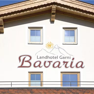 A country hotel named "Bavaria" on the facade. It has a bright wall and three windows, as well as a traditional roof.
