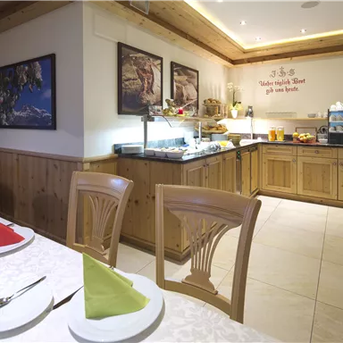 An inviting restaurant with wooden decor and bright walls. A variety of dishes are available at the buffet, while table decorations are colored in red and green.