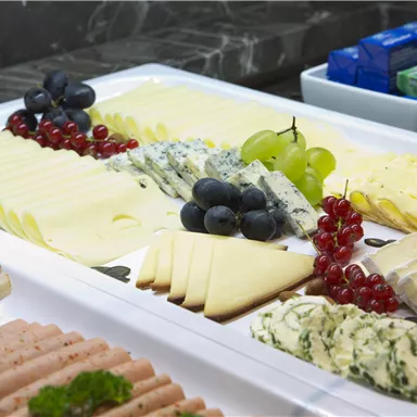 A lavish cheese and sausage platter with grapes and red currants.
A variety of cheese and sausage arrangements on an elegant white plate.