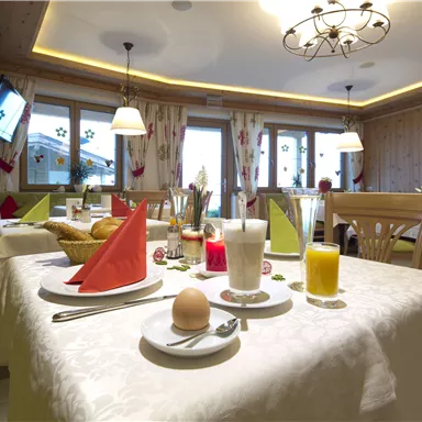 A cozy breakfast in a bright restaurant. The table is set with plates, drinks, and fresh rolls.