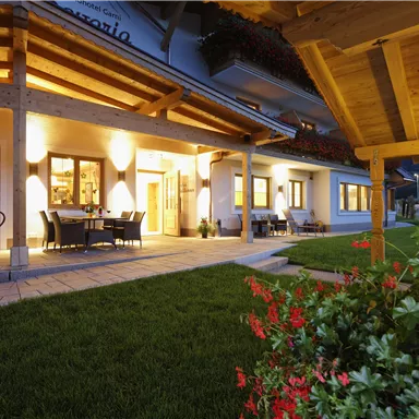 An inviting building with wooden architecture and a illuminated entrance area. The well-maintained garden invites you to linger.