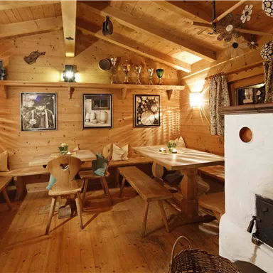 A cozy dining room with wood decor and rustic tables. Pictures hang on the walls, and the atmosphere is warm and inviting.