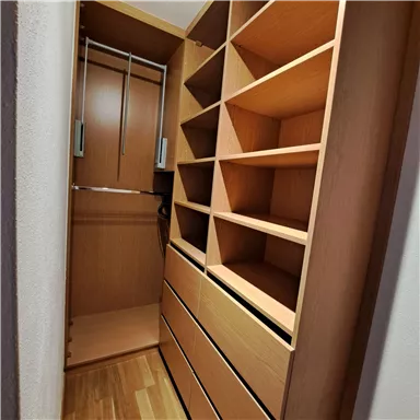 A well-organized wooden wardrobe with shelves and drawers. The interior design is bright and modern.