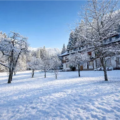 A snow-covered house in a winter landscape. The trees and the ground are covered with a thick layer of snow.