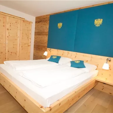 Ein modernes Schlafzimmer mit einem großen Doppelbett und Holzverkleidung. Die Wände sind in ruhigen Farben gehalten, und es gibt einen geräumigen Kleiderschrank.