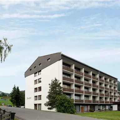 A modern building with several floors in a rural setting. Surrounded by trees and gentle hills, it offers a tranquil atmosphere.