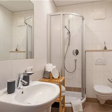 A modern bathroom with a shower unit and a sink. The bright furnishings create a pleasant atmosphere.
