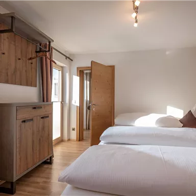 Ein modernes Zimmer mit zwei Einzelbetten und Holzverkleidung. Große Fenster und helle Farben schaffen eine einladende Atmosphäre.