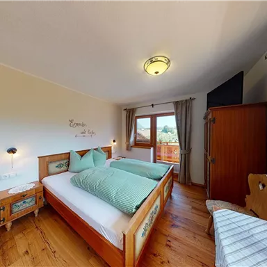 Ein gemütliches Schlafzimmer mit zwei Betten und Holzverkleidung. Das Zimmer hat große Fenster, die einen Blick ins Freie bieten.