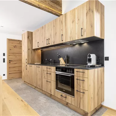 A modern kitchen with wooden cabinets and elegant surfaces. It is well-equipped and has plenty of storage space.