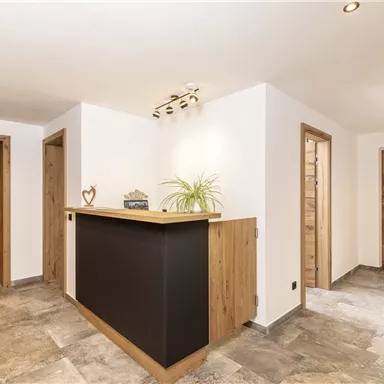 A modern reception area with a wooden counter and white walls. The environment is bright and friendly with an elegant floor.