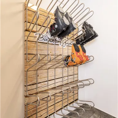 A modern ski boot rack made of wood and metal. It provides space for several pairs of ski or snowboard boots.