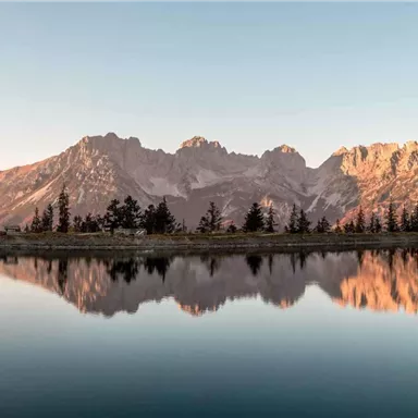 A stunning mountain landscape with reflecting peaks in the water. The sky is clear and the natural scene radiates tranquility.