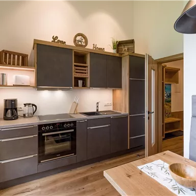 Eine moderne Küche mit dunklen Schränken und Holzdetails. Sie ist gut ausgestattet mit Geräten und hat eine helle, einladende Atmosphäre.