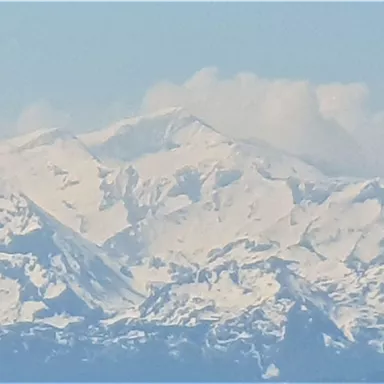 Eine beeindruckende Berglandschaft mit schneebedeckten Gipfeln und blauen Himmel. Die majestätischen Berge strahlen Ruhe und Erhabenheit aus.