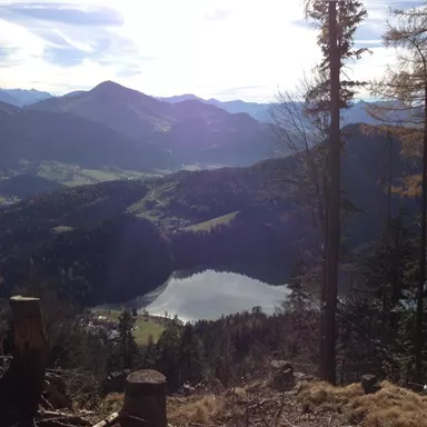 A magnificent mountain landscape with a sparkling lake in the foreground. The sky is clear and the mountains rise majestically in the background.