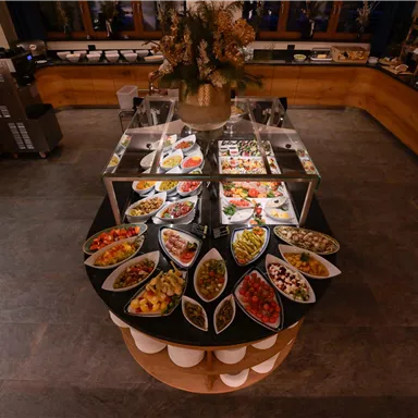 Ein Buffet mit einer Vielzahl von Gerichten in eleganten Schalen. Die Auswahl umfasst frisches Obst, Gemüse und andere Köstlichkeiten.