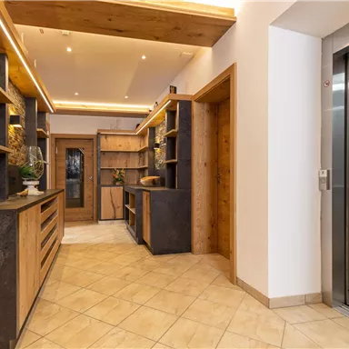 A modern reception area with wooden shelves and elegant furniture. On the right side, there is an elevator.