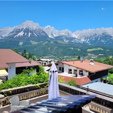 Ein schöner Blick auf die Berge mit klaren blauen Himmel. Im Vordergrund sind Häuser und eine Sonnenschirm.