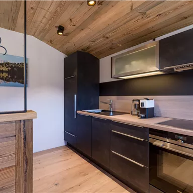 Moderne Küche mit Holzverkleidung und eleganten Geräten. Helle Farben und eine gemütliche Atmosphäre prägen den Raum.