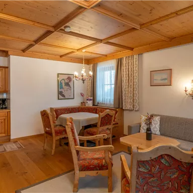 A cozy living space with a modern kitchenette and a dining area. Bright walls and a relaxing wooden ceiling create an inviting atmosphere.