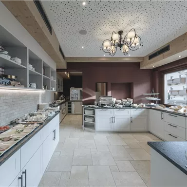 A modern kitchen with bright walls and a spacious dining area. Various dishes and drinks are arranged on the tables.