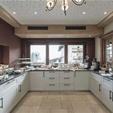 A modern breakfast buffet in a bright room. The large windows offer a view of the landscape outside.