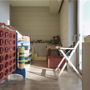 A cozy play area with colorful toys and a chair. The room has large windows and plenty of natural light.