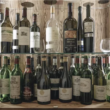 A wine cabinet with various bottles of wine on two shelves. The bottles are well organized and some glasses are also visible.