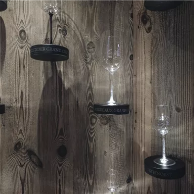 A wooden wall with hanging wine glasses in various sizes. The glasses are labeled with black markings.