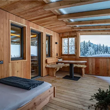 A cozy wooden porch with a view of snow-covered trees. The room is bright and inviting, perfect for relaxation.