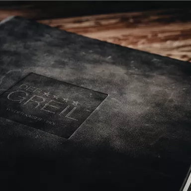 A black notebook with an embossed logo. The surface has an elegant, matte texture.