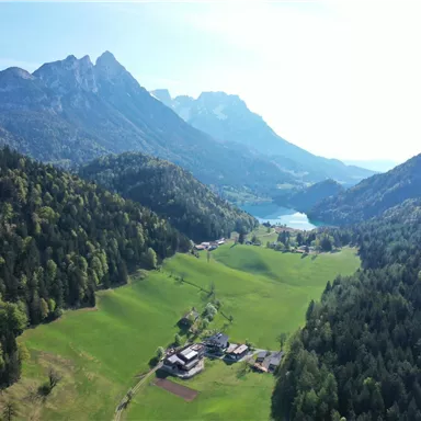 A picturesque landscape with green meadows, mountains, and a clear lake. The natural beauty of the surroundings radiates tranquility and peace.